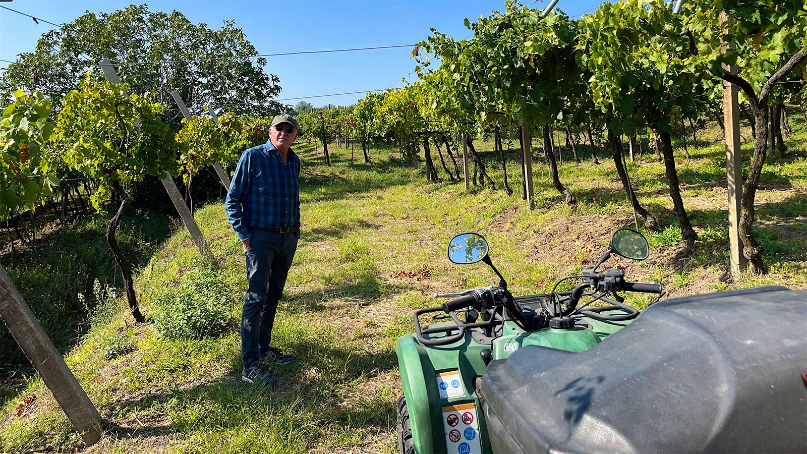 Graziano Prà stands between sloping rows of vines in Soave Classico, with his ATV parked in the foreground
